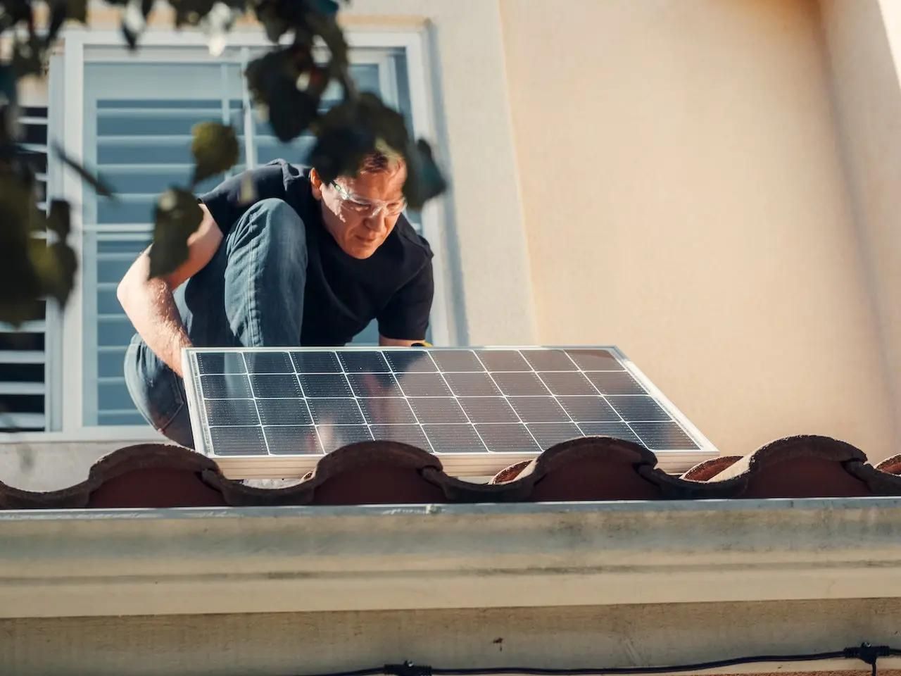Ein Solarpaneel wird von einem Handwerker auf einem Dach montiert.