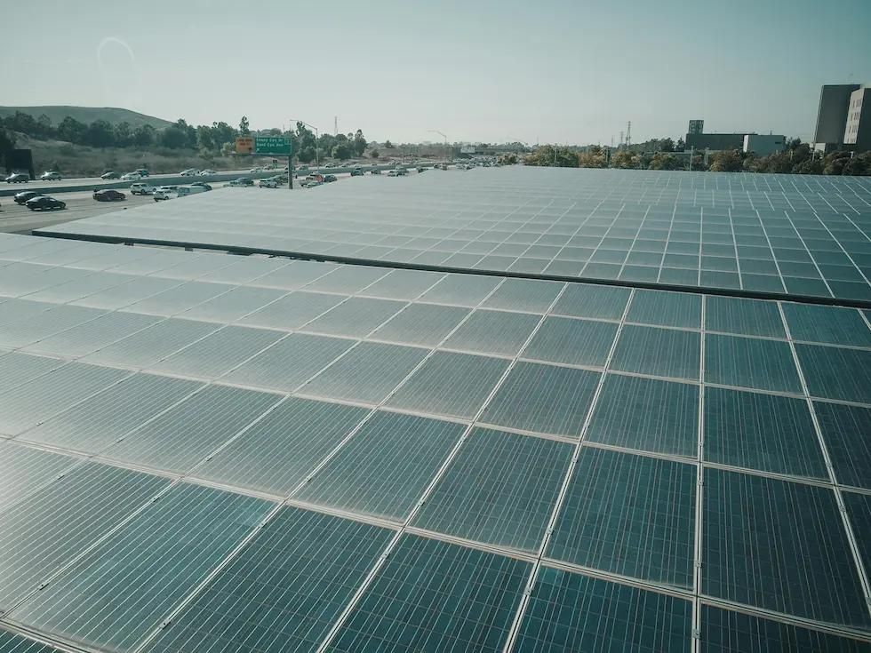 Mehrere Reihen mit PV-Modulen neben einer Straße.