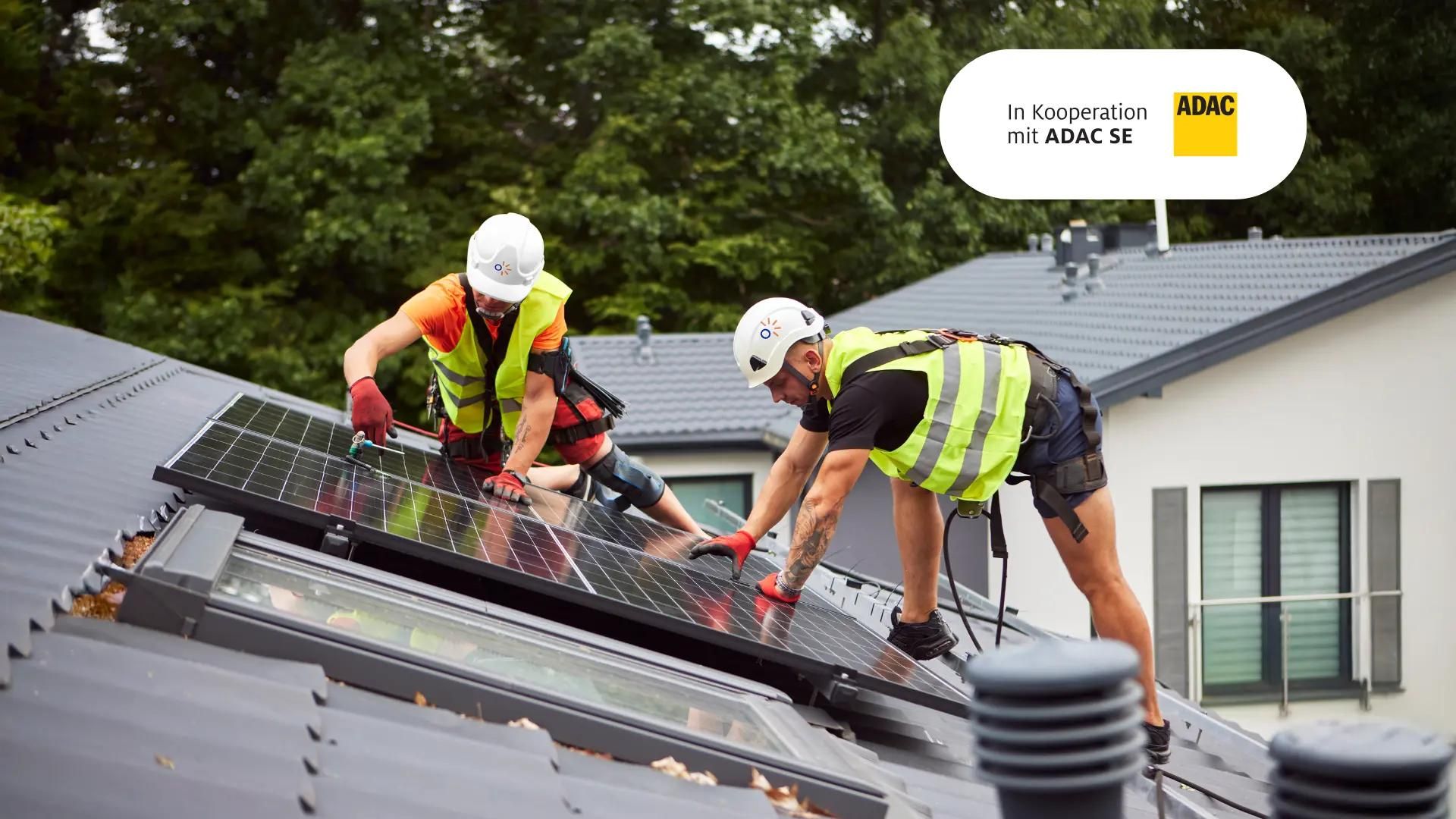 Zwei Solarteure auf dem Dach eines Hauses, arbeiten an Solarmodulen.