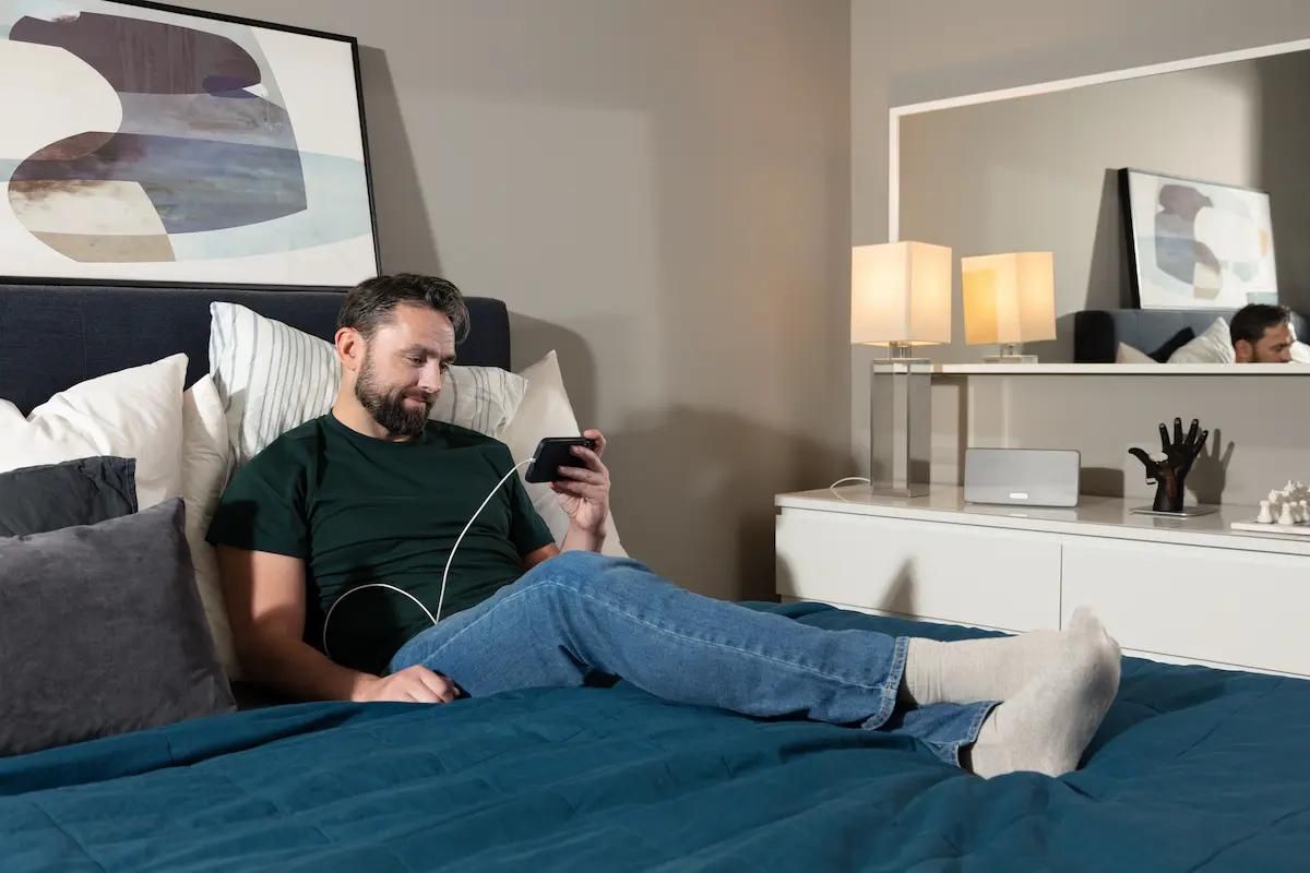 Person liegt im Bett und scrollt auf ihrem Handy