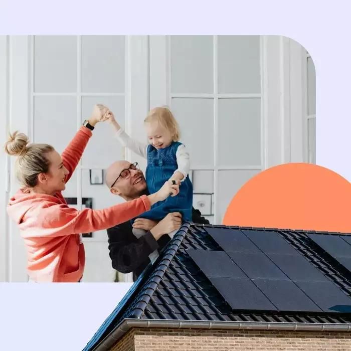 Ein Paar spielt mit einem Kind, im Vordergrund sieht man eine PV-Anlage auf dem Dach eines Einfamilienhauses.